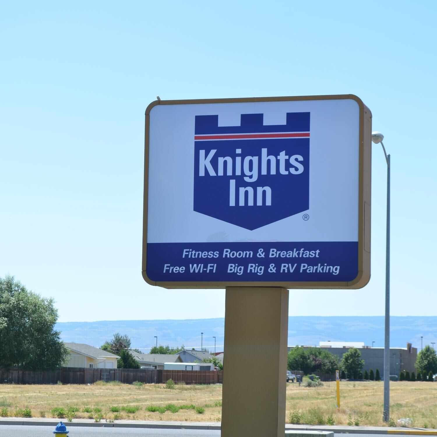 A Knights Inn signboard with amenities including a fitness room, breakfast, free Wi-Fi, big rig & RV parking.