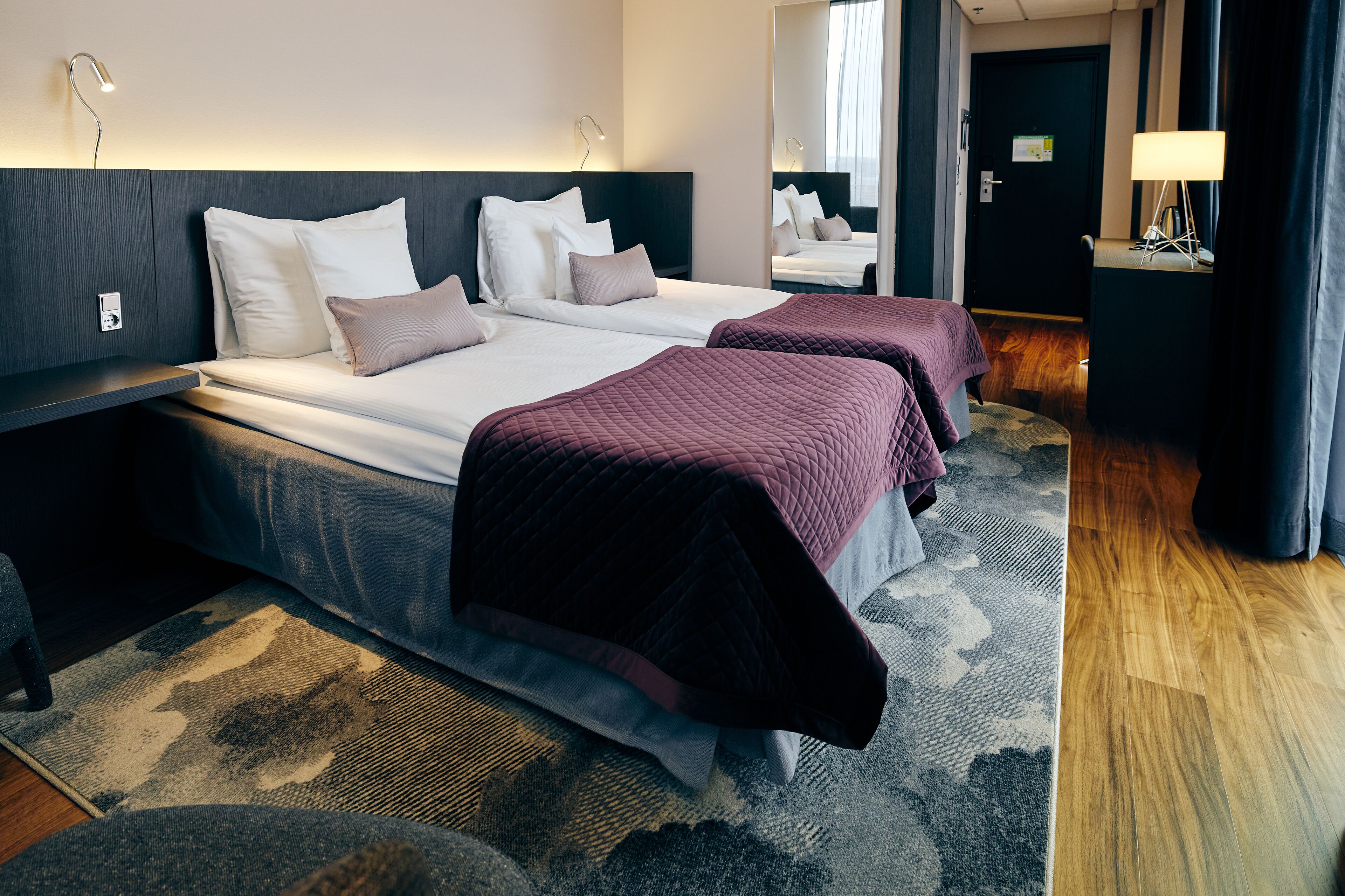 Habitación de hotel con dos camas, un escritorio y un espejo.