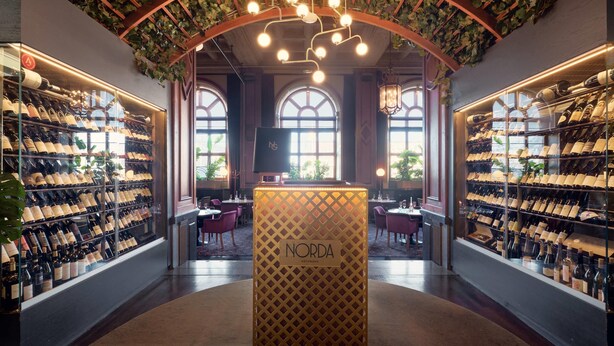 A wine cellar with shelves of wine bottles, a central display case labeled "Norda", and a ceiling with hanging lights and greenery. - Clarion Hotel Post, Gothenburg (Gothenburg)
