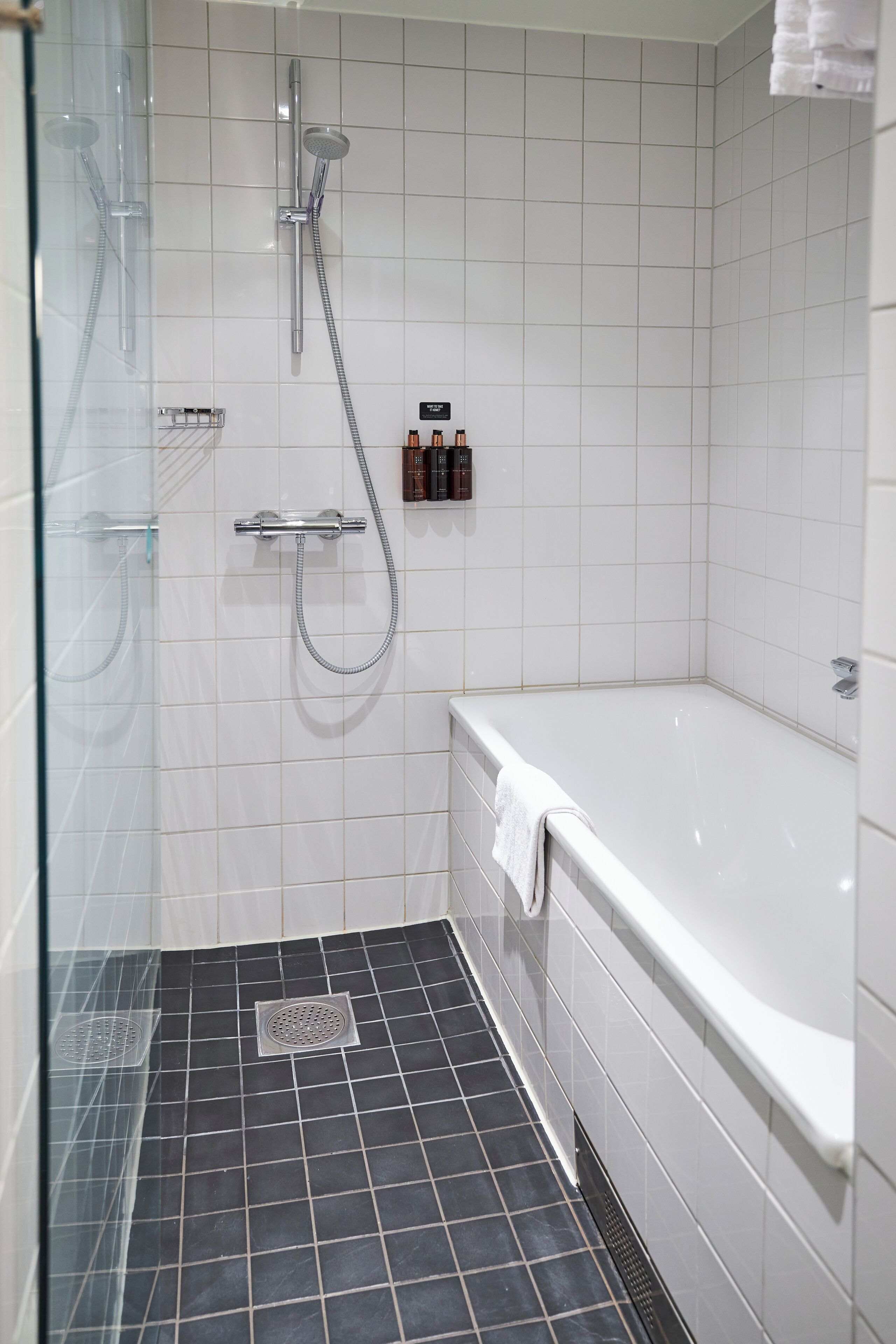 A modern bathroom with a glass shower enclosure, a separate bathtub, and a tiled floor.