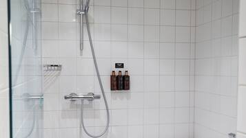 A modern bathroom with a glass shower enclosure, a separate bathtub, and a tiled floor.