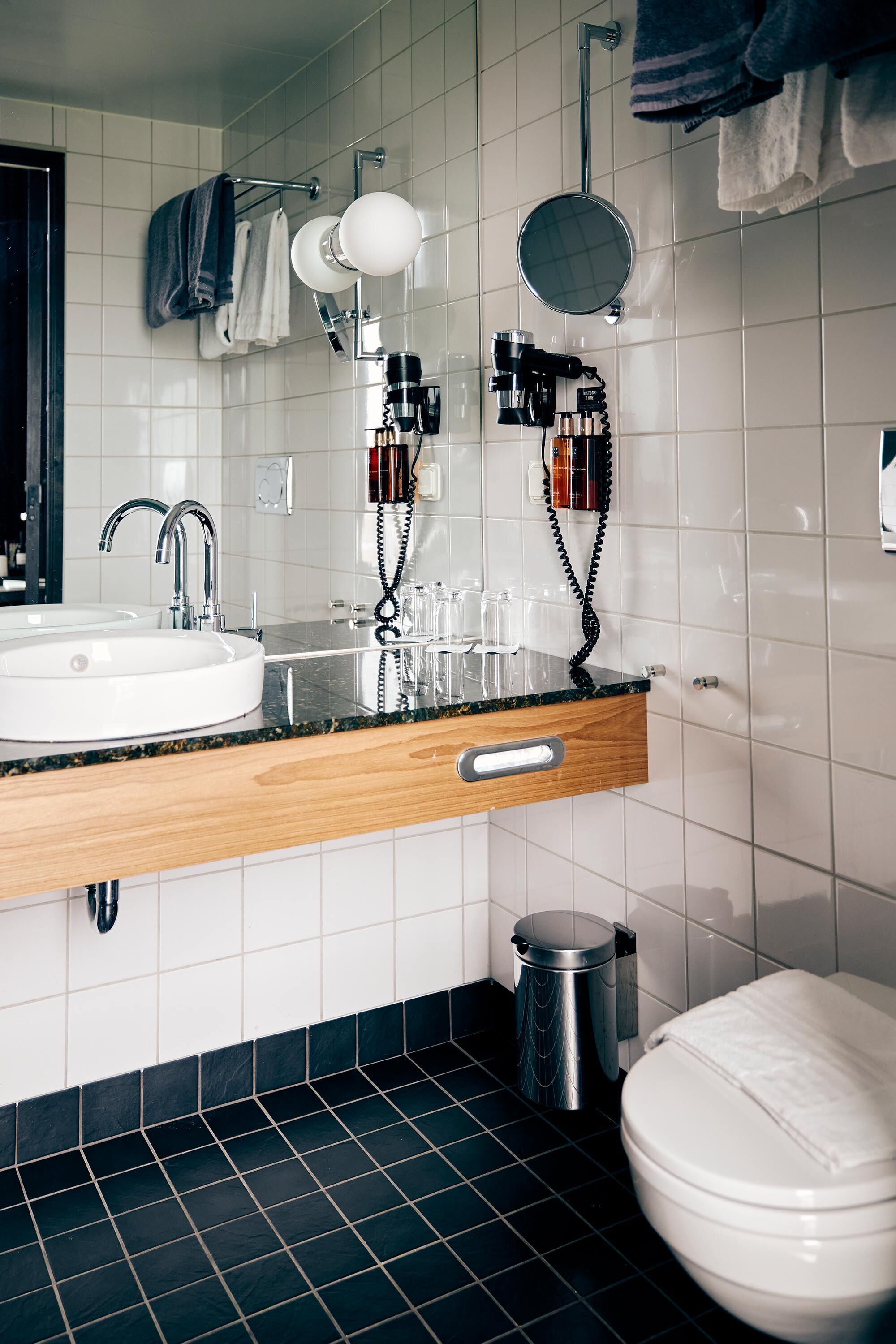 A modern bathroom with a white sink, a mirror, and a toilet.