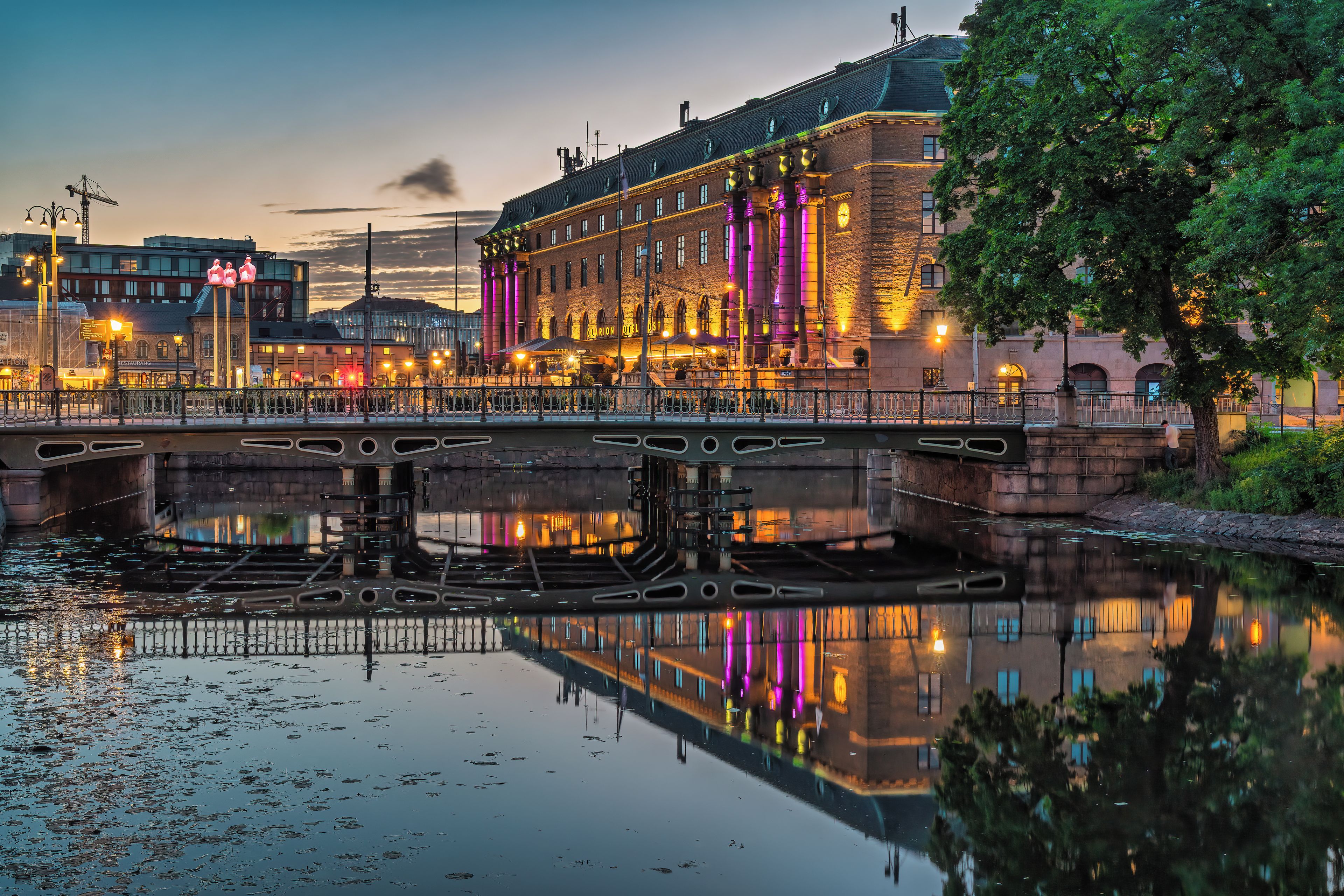 A historic building with a bridge over a canal, featuring a reflection in the water.