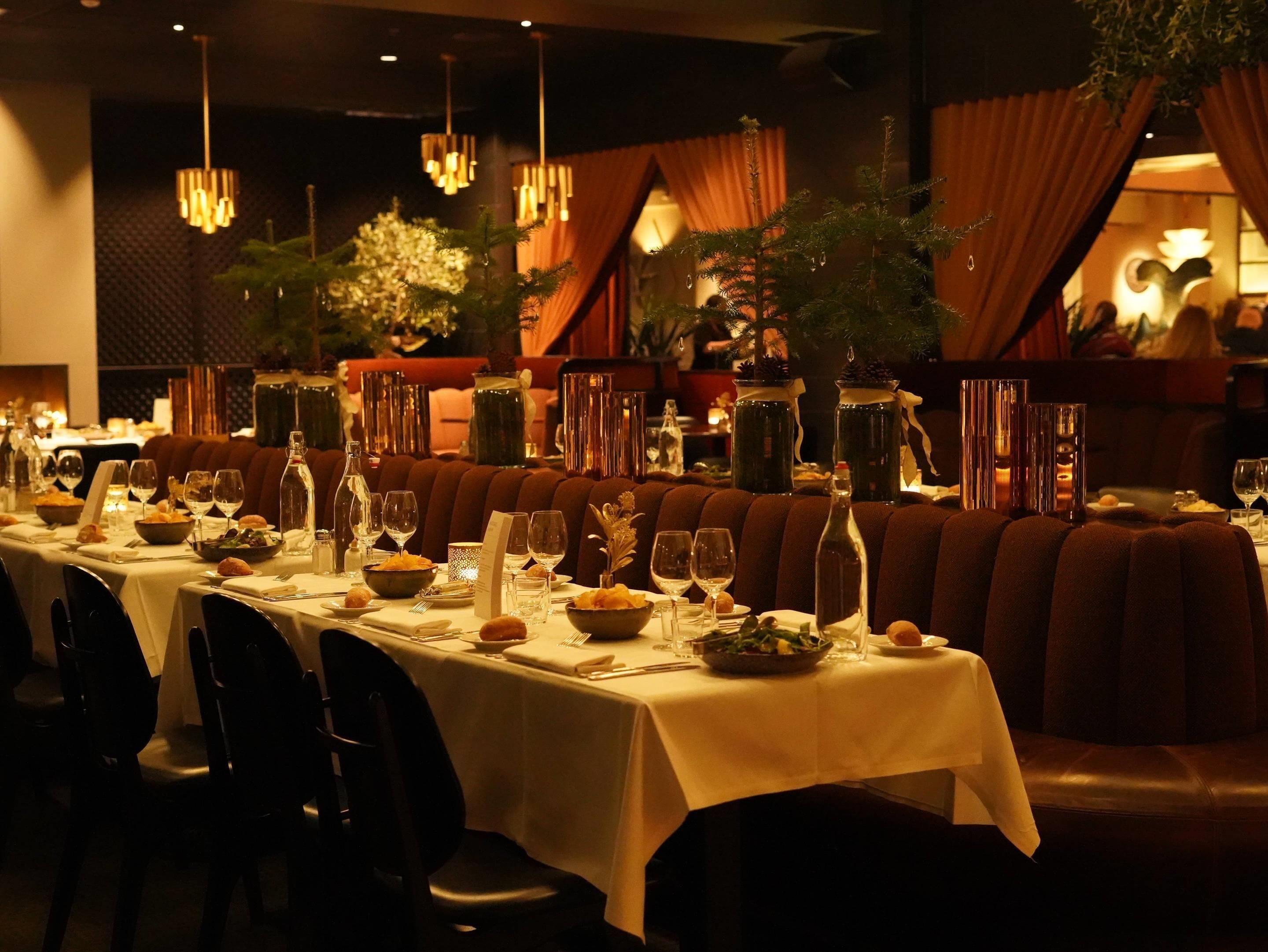 A restaurant with long tables set for dining, featuring candlelit centerpieces and a warm ambiance.