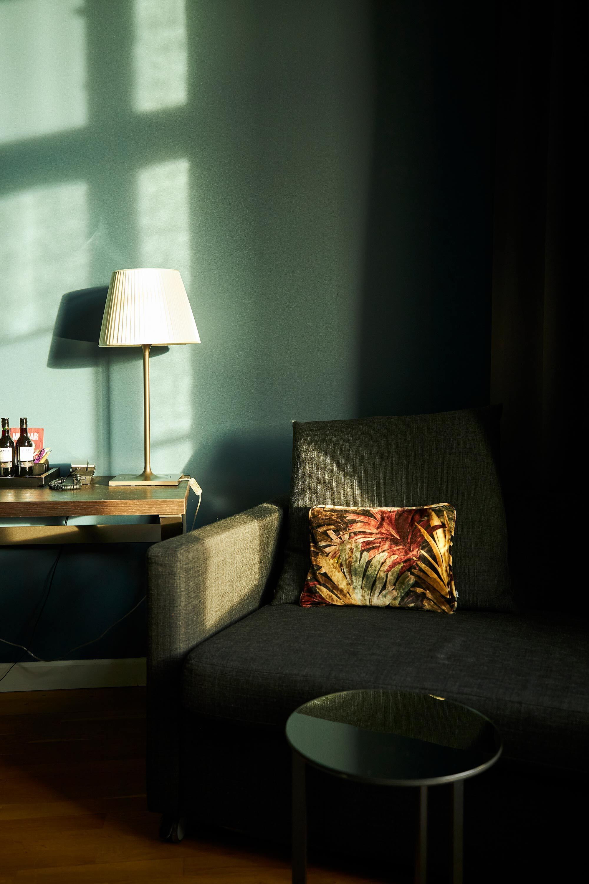A modern living room with a sofa, a small round table, and a lamp.