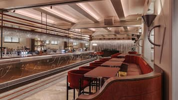 En modern restaurang med en bardel, röda sittplatser och en elegant bardisk.