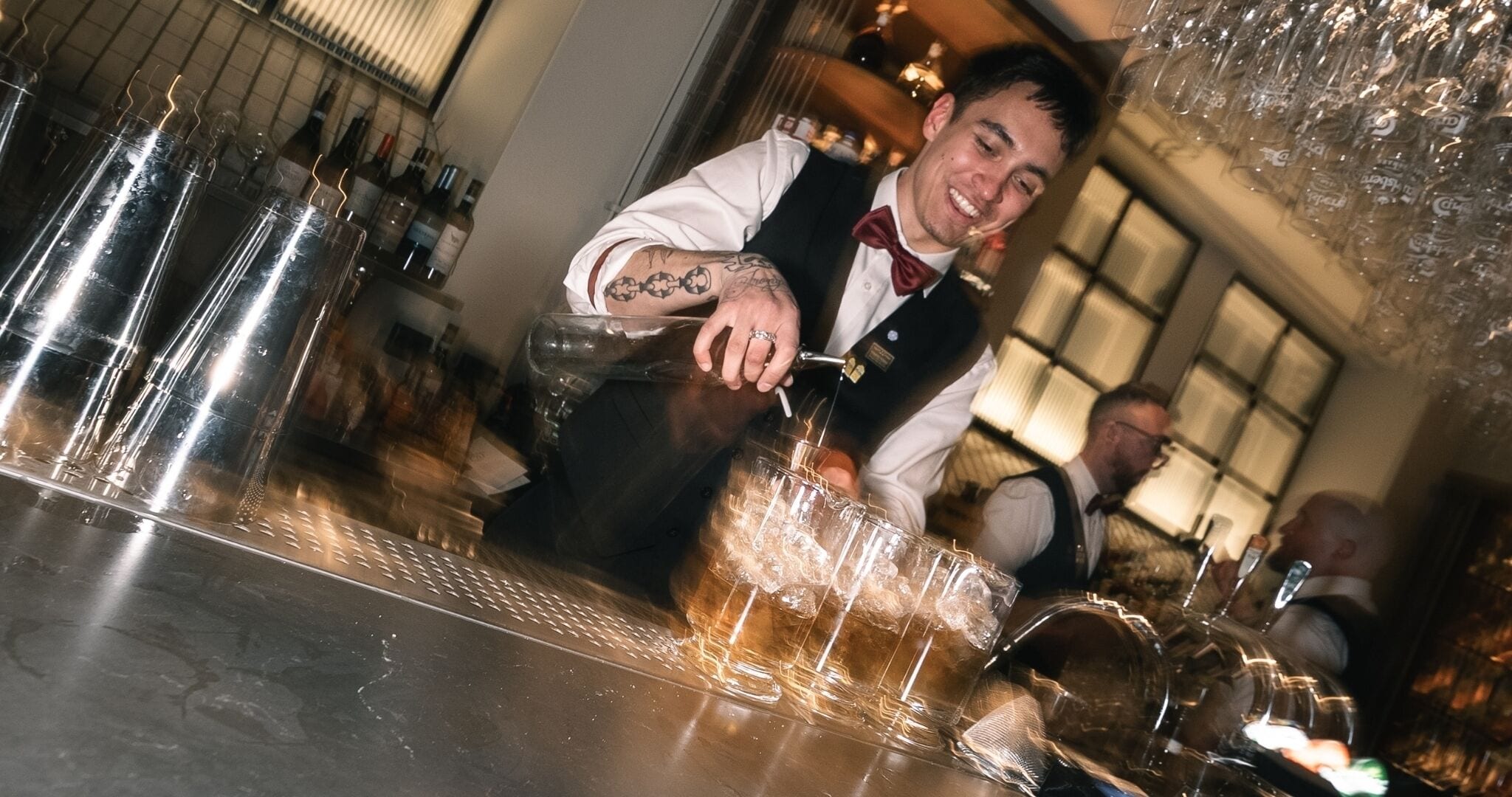 A bartender pouring a drink into a glass at a bar.