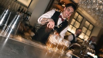 A bartender pouring a drink into a glass at a bar.