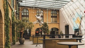 An indoor space with brick walls, large windows, and a hanging sculpture. Tables and chairs are arranged for seating. - Clarion Hotel Post, Gothenburg (Gothenburg)