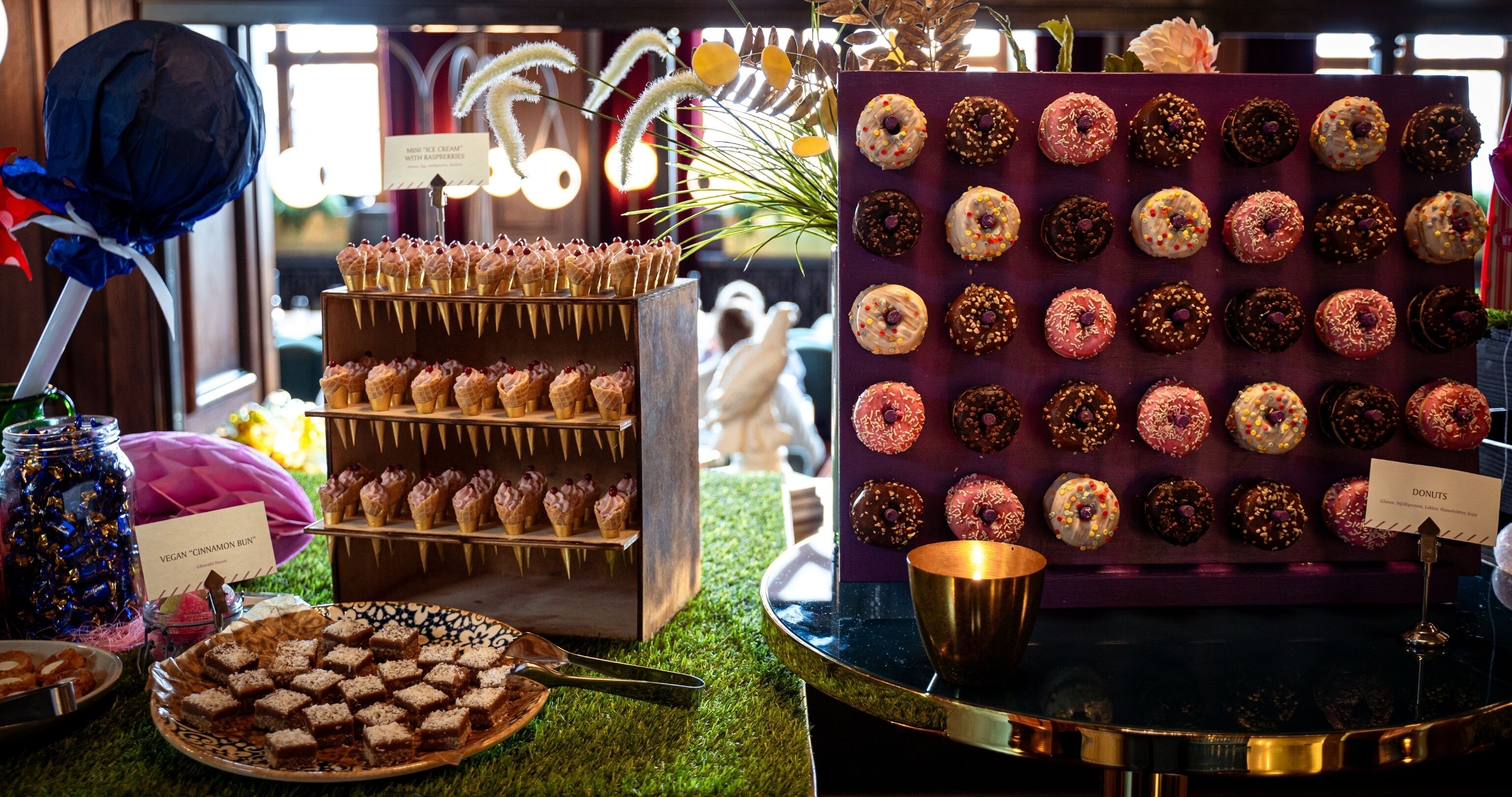 Exhibición de postres con diversos dulces y un cartel que indica 'Donuts'.