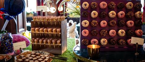 Exhibición de postres con diversos dulces y un cartel que indica 'Donuts'.
