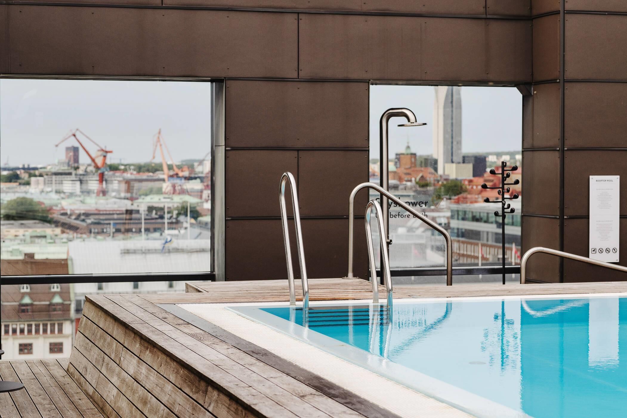 Una piscina interior con vistas a una obra en construcción y un edificio alto al fondo.