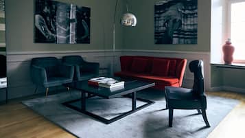 Una sala de estar con un sofá rojo, dos sillones, una mesa de centro y arte abstracto en las paredes.