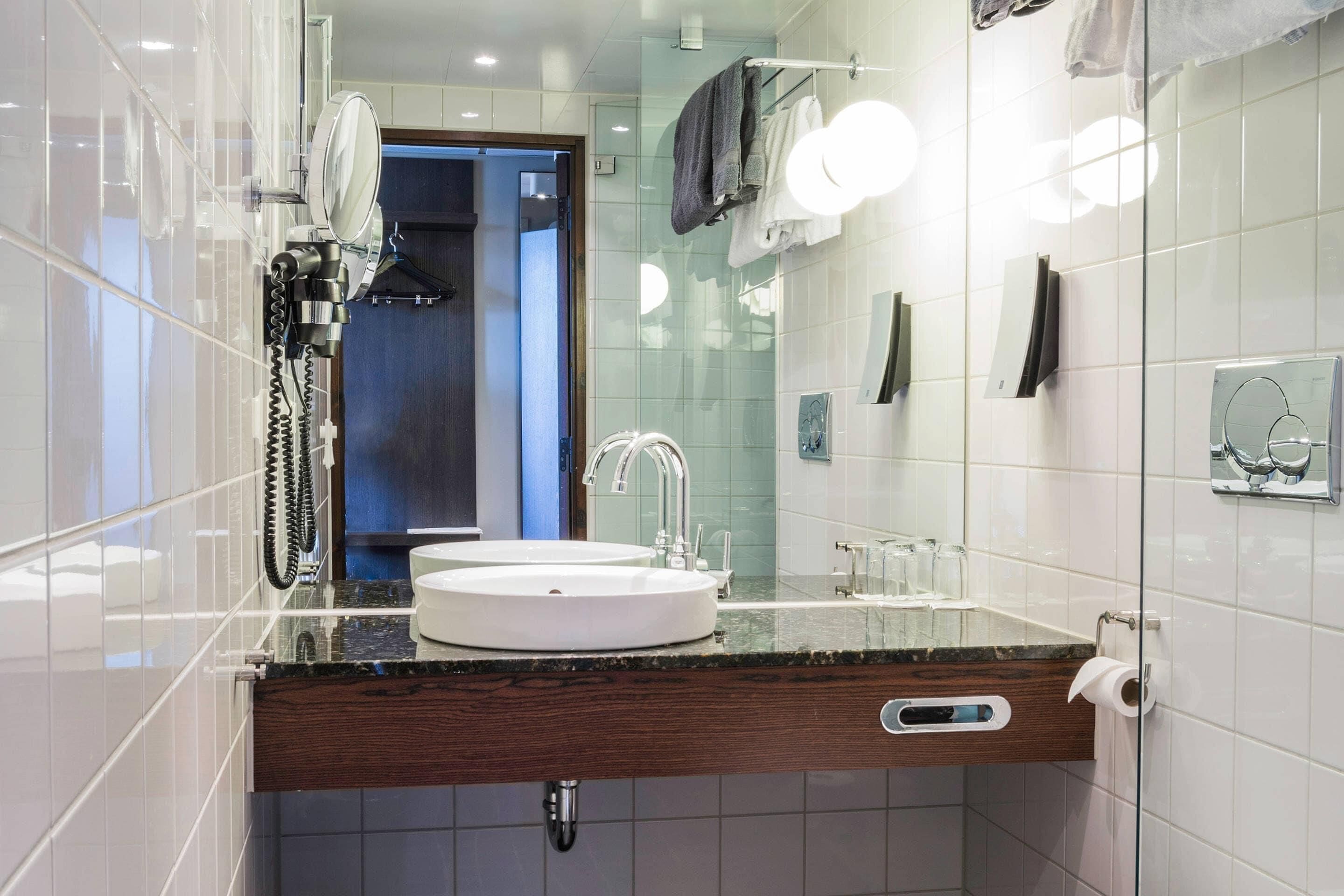 Un baño moderno con lavamanos doble, espejo y toallero.