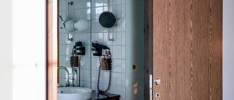 Un baño con puerta de madera, un lavabo y un espejo.