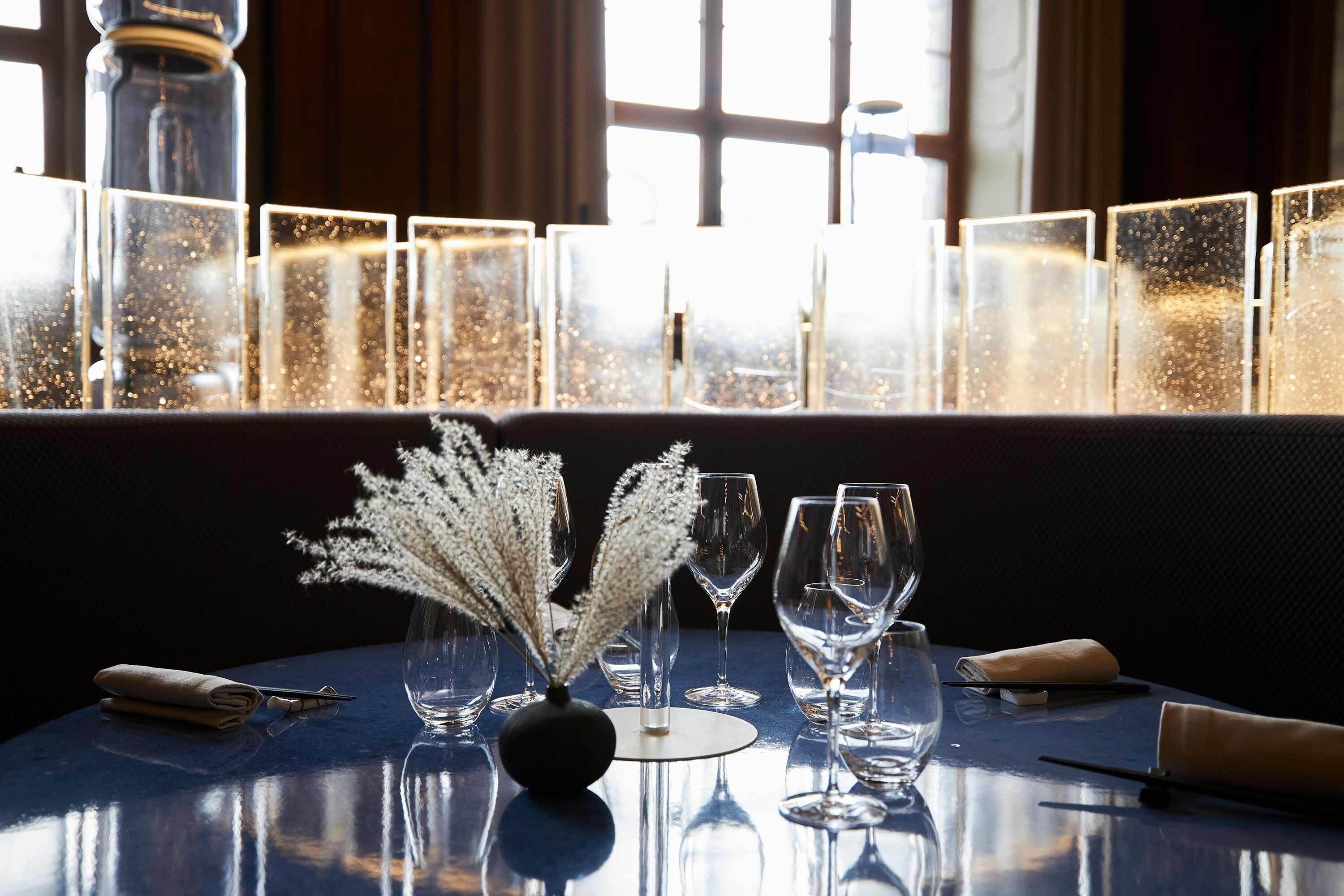 Una mesa dispuesta con copas de vino, un jarrón con flores secas y un candelabro.