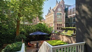 Un patio con cubierta de madera, una zona de estar y un edificio de estilo arquitectónico tradicional.