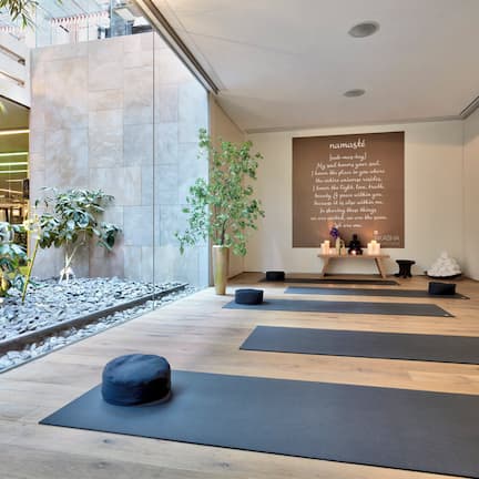 A modern yoga studio with wooden floors, black mats, and a large wall with a motivational quote.