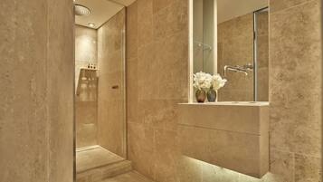 A modern bathroom with a glass-enclosed shower, a vanity with a mirror, and a vase with flowers.