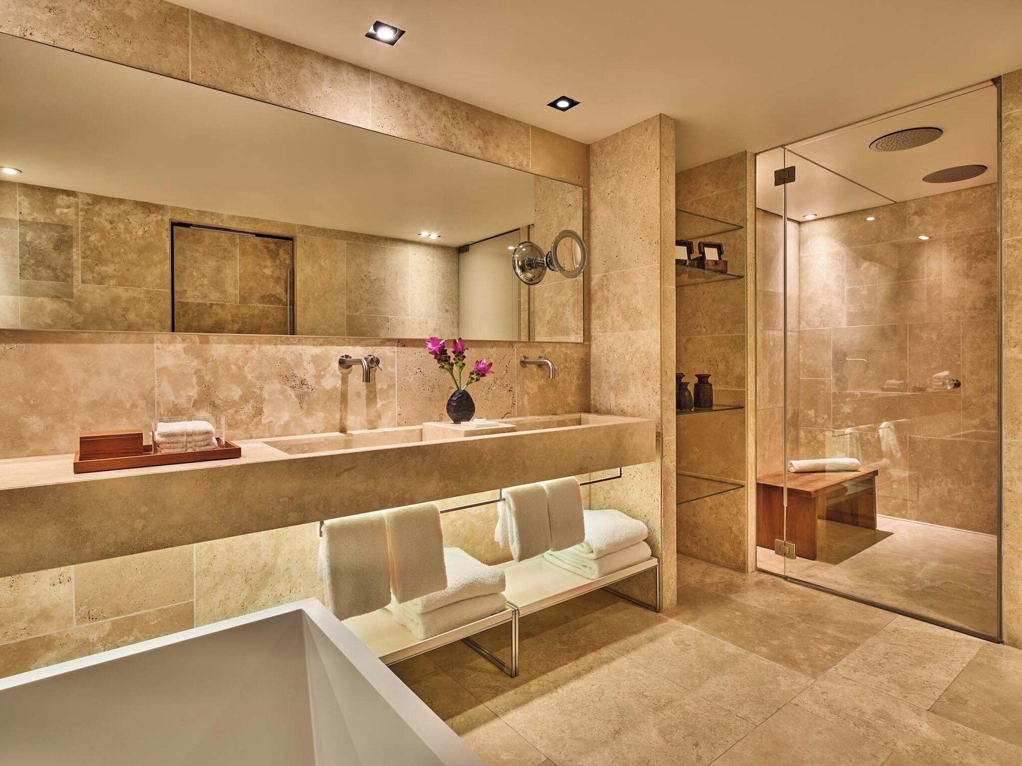 A modern bathroom with a large mirror, a bathtub, a shower area, and a vanity with a sink and towel rack.
