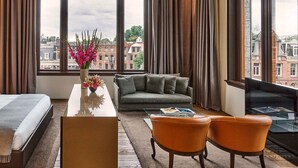 A hotel room with a large window, a sofa, two chairs, a desk, and a bed. - Mandarin Oriental Conservatorium, Amsterdam (Amsterdam)