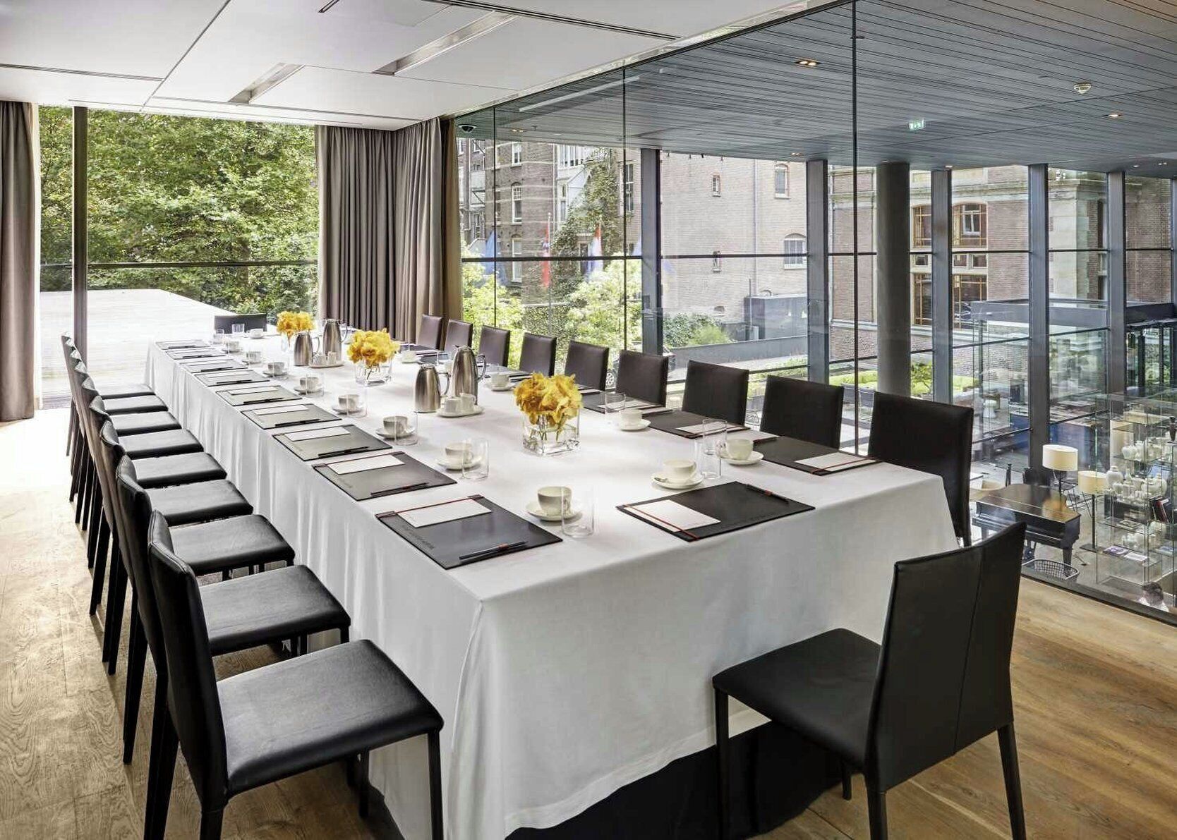 A conference room with a long table set for a meeting, large windows with a city view, and modern interior design.