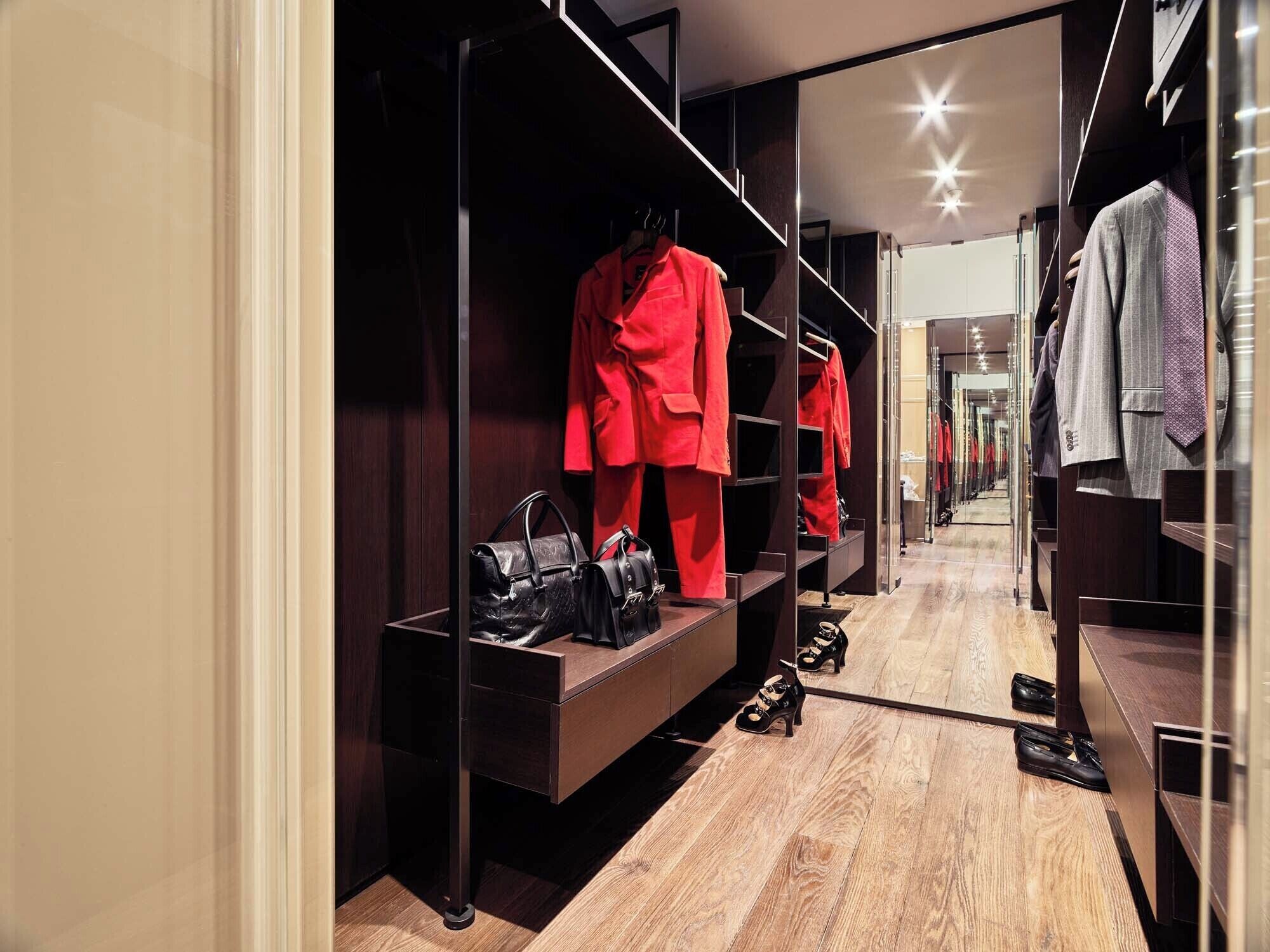 Un vestidor moderno y bien iluminado, con estantes organizados y un espejo.