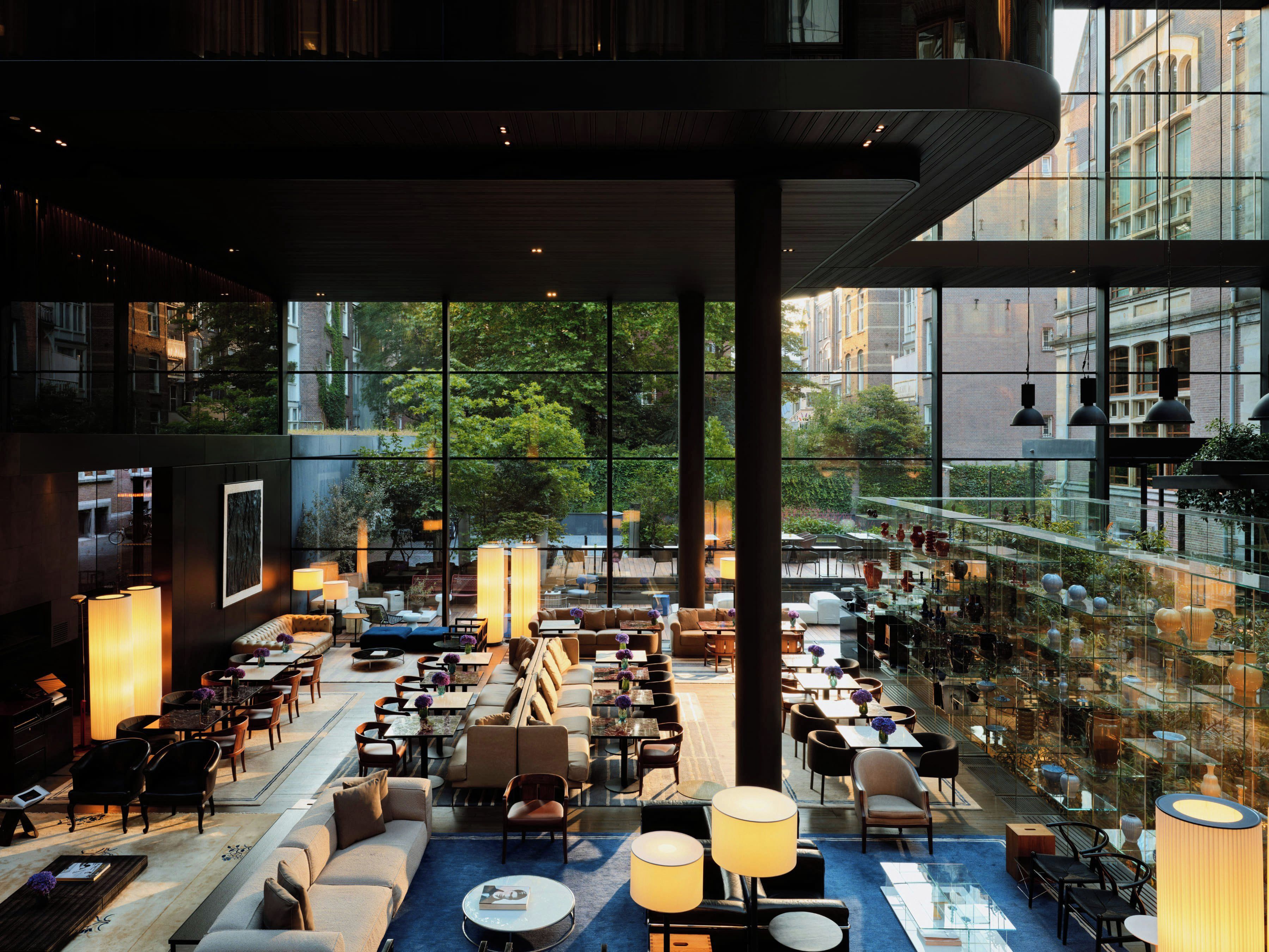 Un espacio interior amplio con diversas opciones de asientos, ventanas grandes y vistas de los edificios circundantes.
