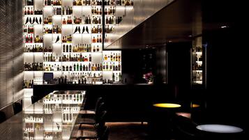 A modern bar area with a reflective bar counter and seating.
