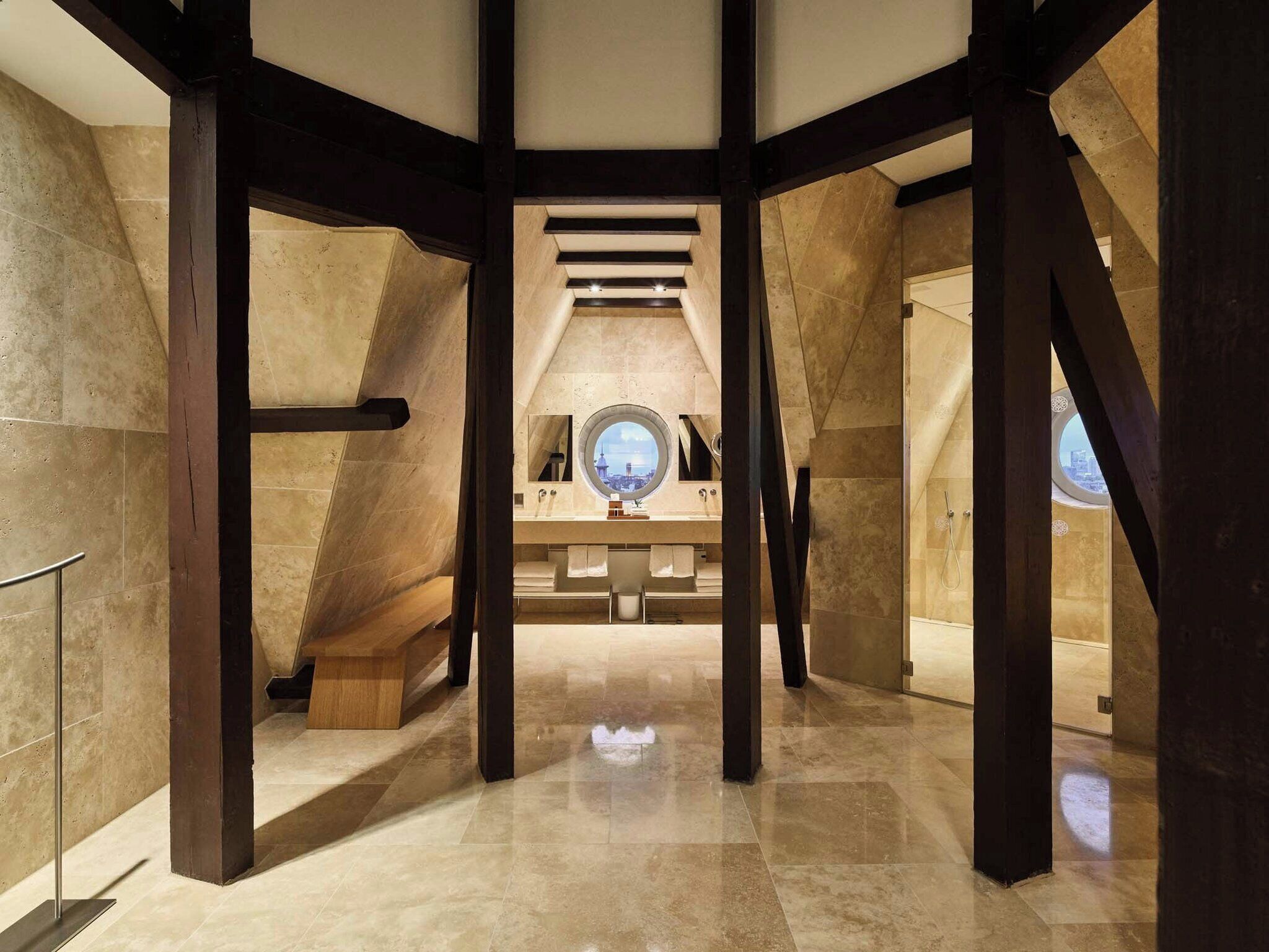An interior view of a modern hotel with a high ceiling, exposed wooden beams, and a central skylight.