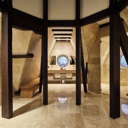 An interior view of a modern hotel with a high ceiling, exposed wooden beams, and a central skylight.