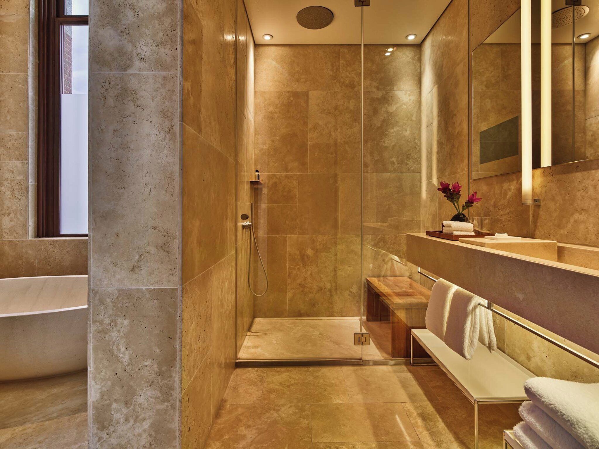 Une salle de bain moderne dotée d’une douche à l’italienne, d’une baignoire et d’un meuble-lavabo avec un miroir.