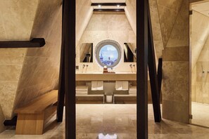 Un baño moderno con tocador, un espejo redondo y vistas de un paisaje urbano reflejado en el espejo.