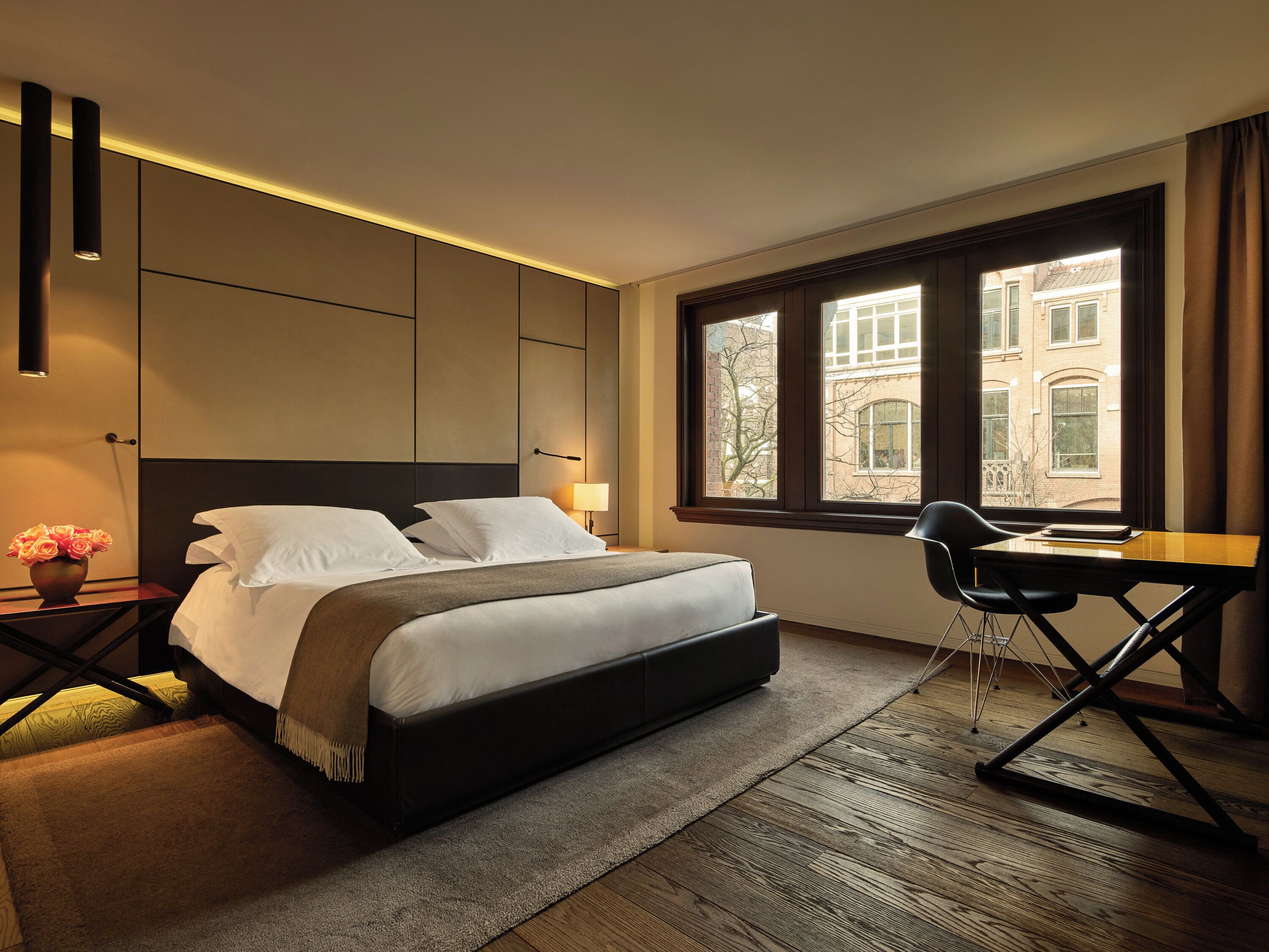 A modern hotel room with a large bed, a desk, and a window with a city view.