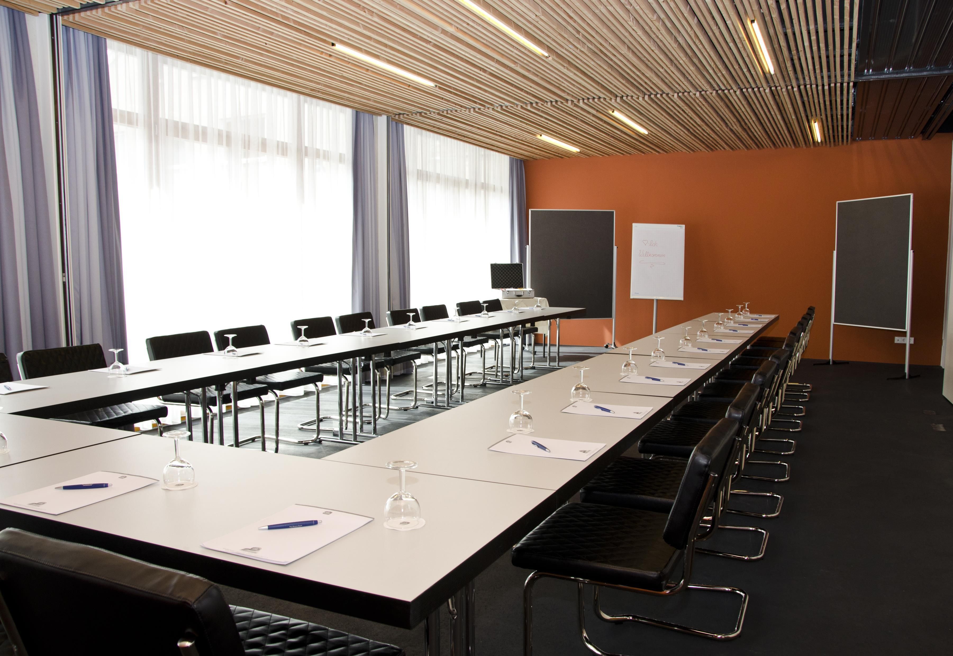 A conference room with a long table, chairs, and presentation screens.