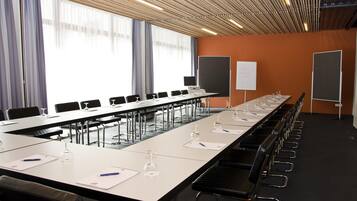 A conference room with a long table, chairs, and presentation screens.