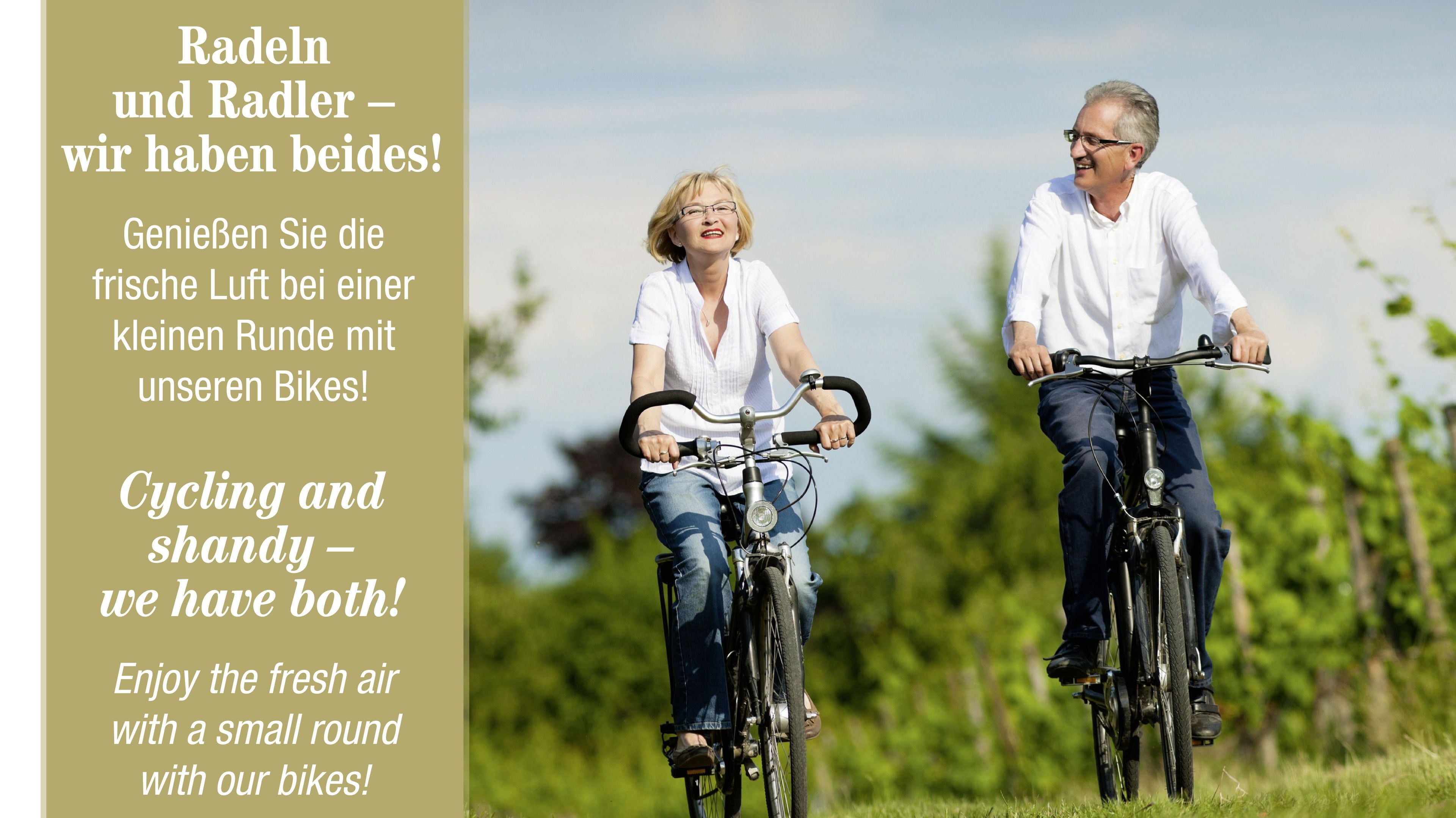 Two people riding bicycles in a grassy area with trees in the background.