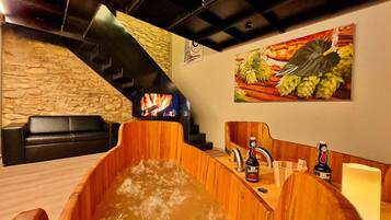 Ein hölzernes Whirlpool mit einer Steinwand und einem Kamin im Hintergrund.