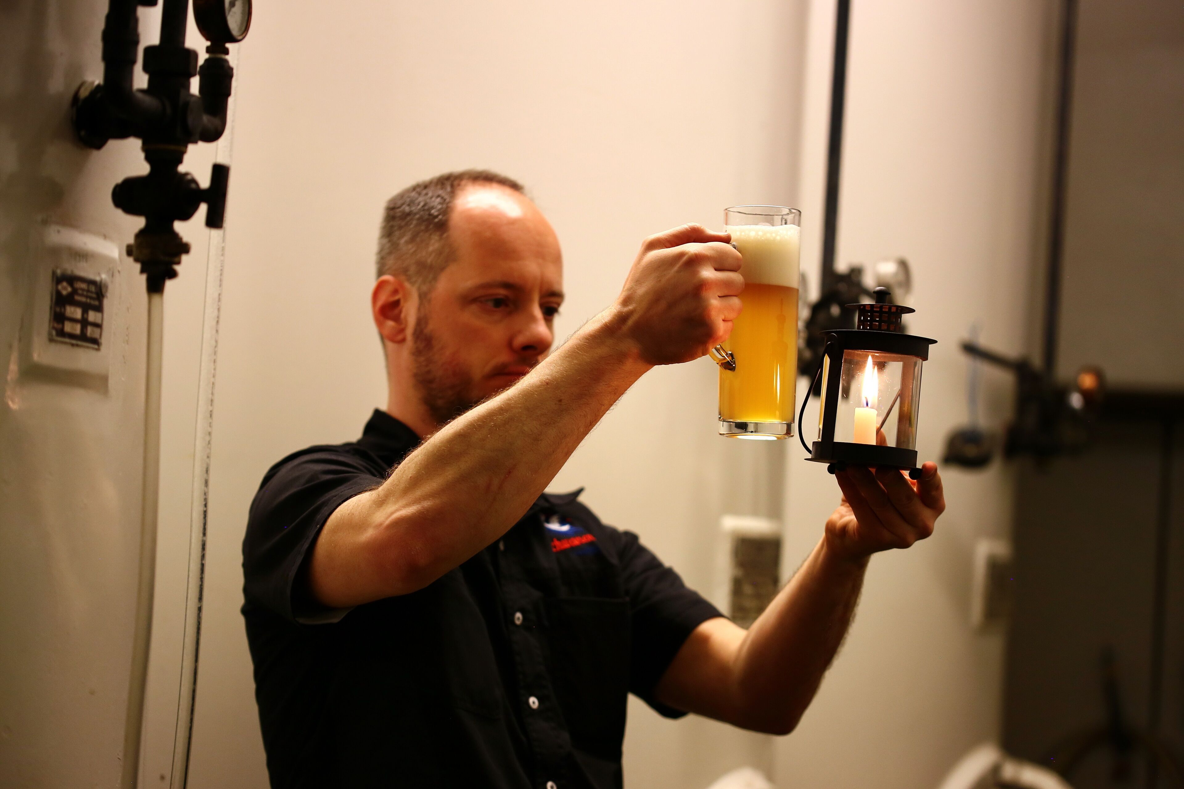 A person holding a beer mug with a candle inside.