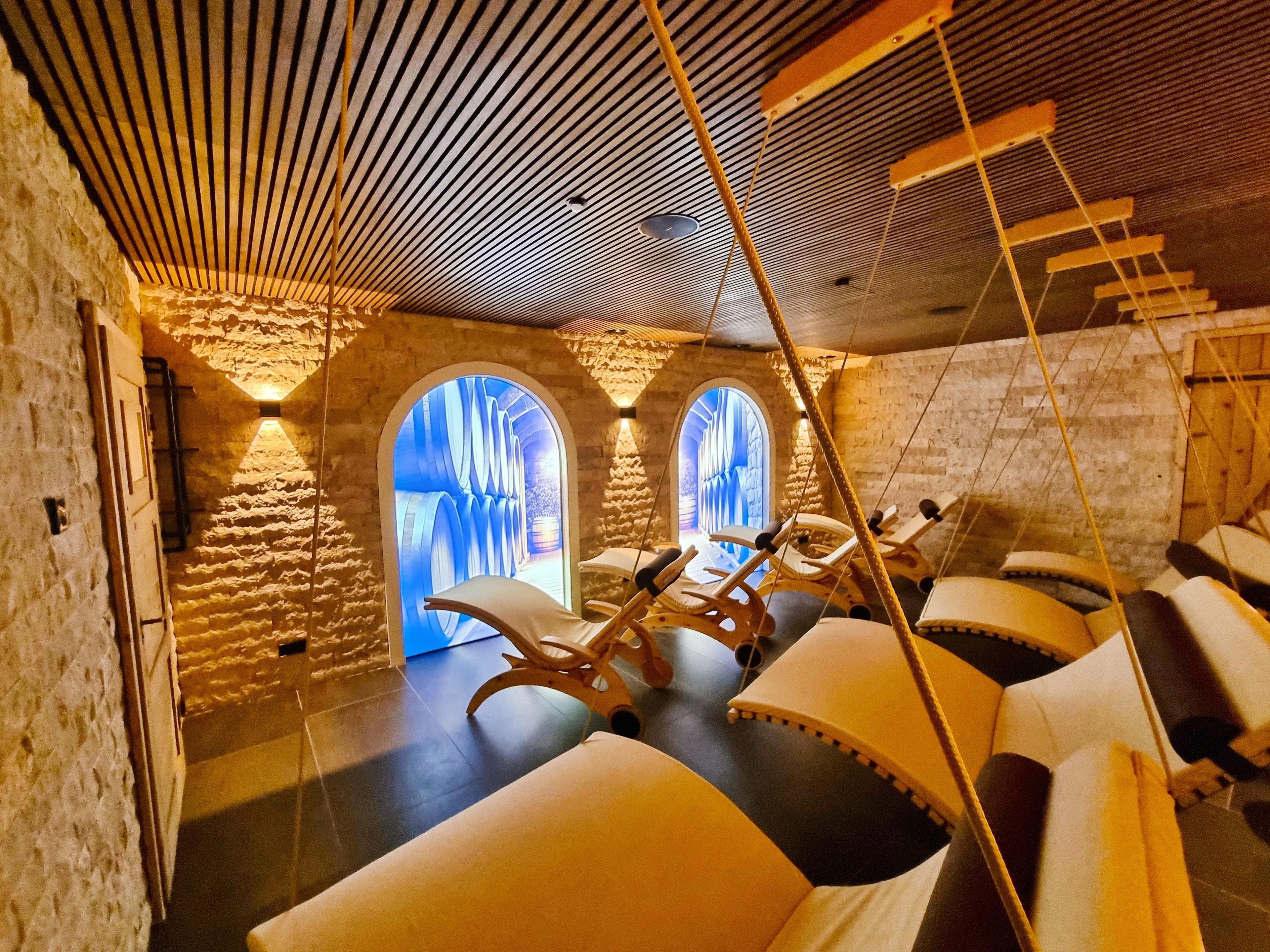 A spa room with stone walls, wooden ceiling, and a massage chair.