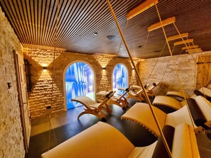 Ein Wellnessraum mit Steinwänden, Holzboden und einem Massagesessel.
