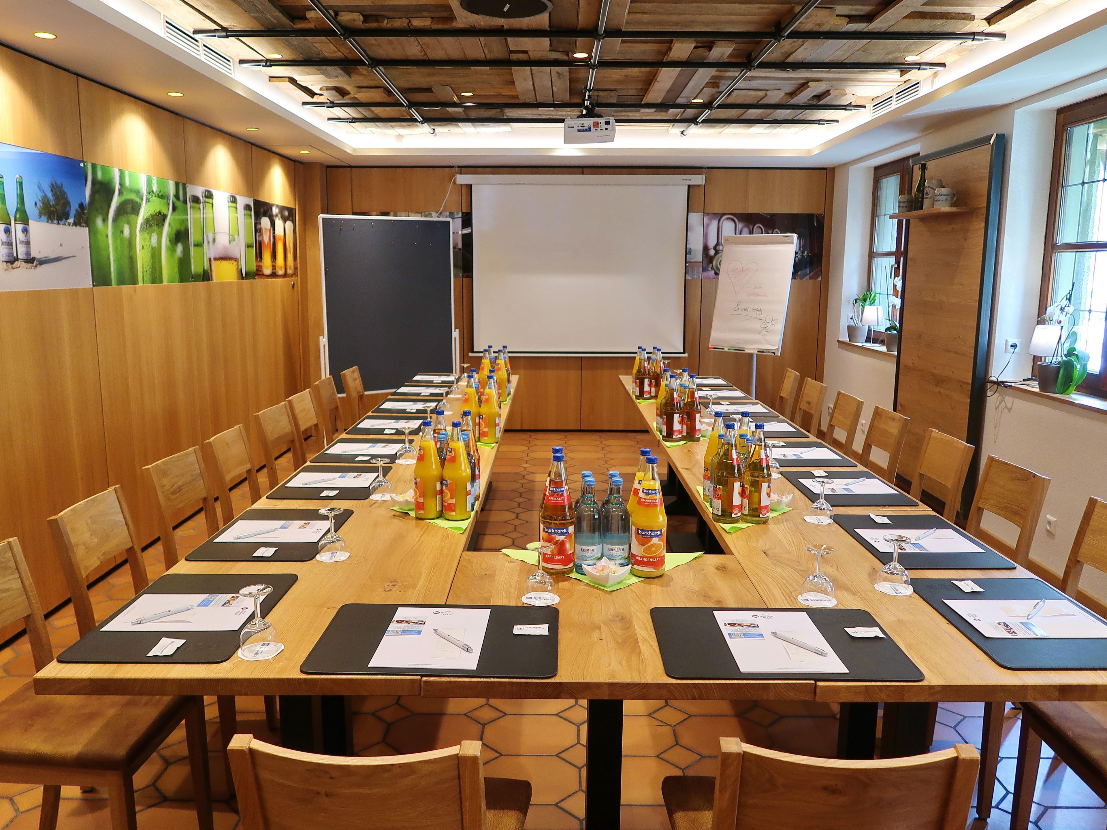 A conference room with a long table, chairs, name cards, and various beverages.