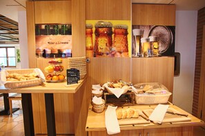 A breakfast buffet with various food items and beverages, including bread, pastries, and a selection of drinks.