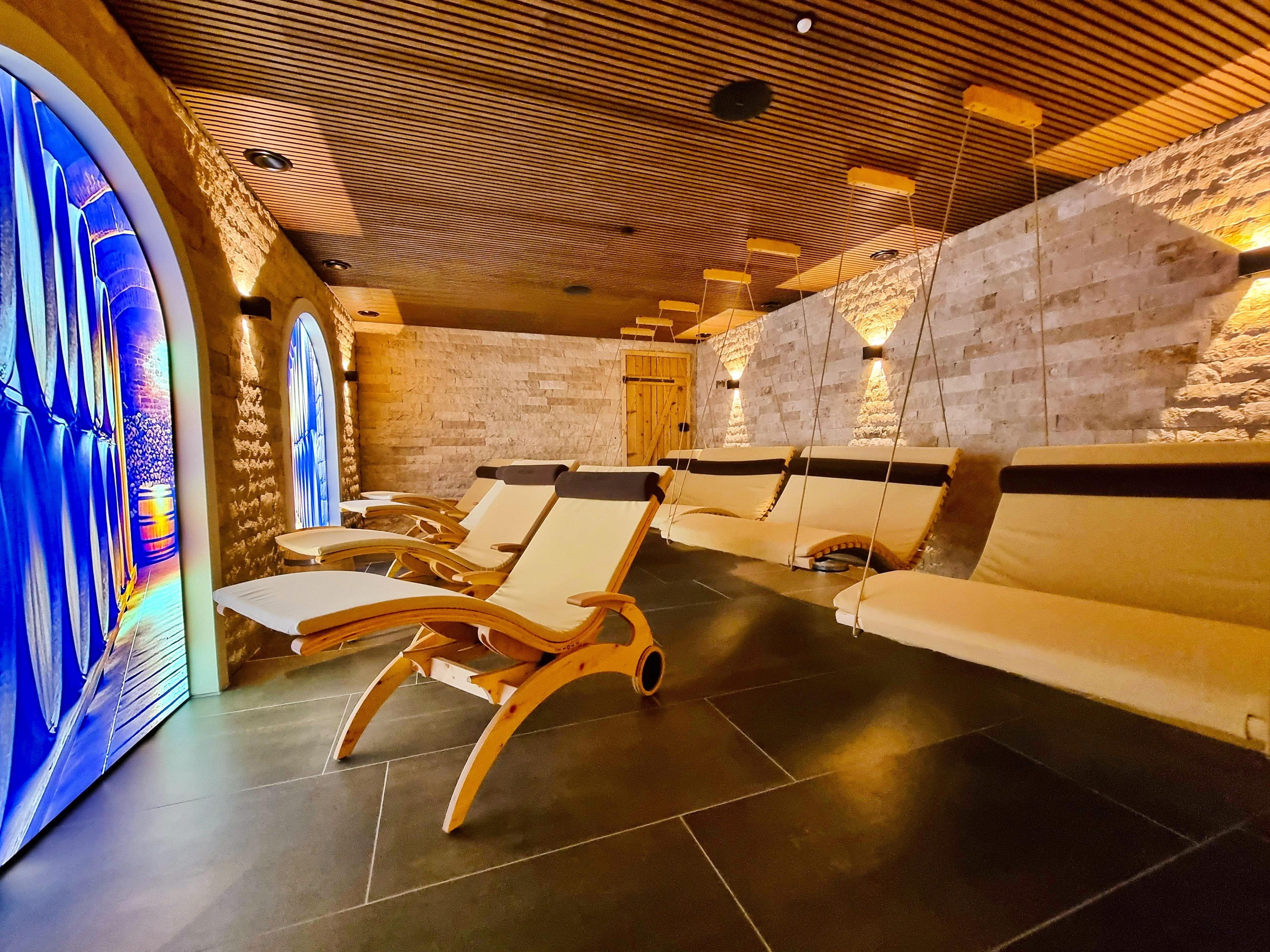 Un espacio de spa con tumbonas de madera y una pared de piedra.