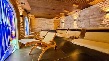 Un espacio de spa con tumbonas de madera y una pared de piedra.
