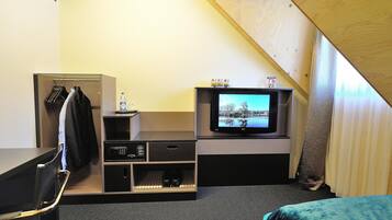 A small room with a television on a stand, a coat rack, and a shoe rack.