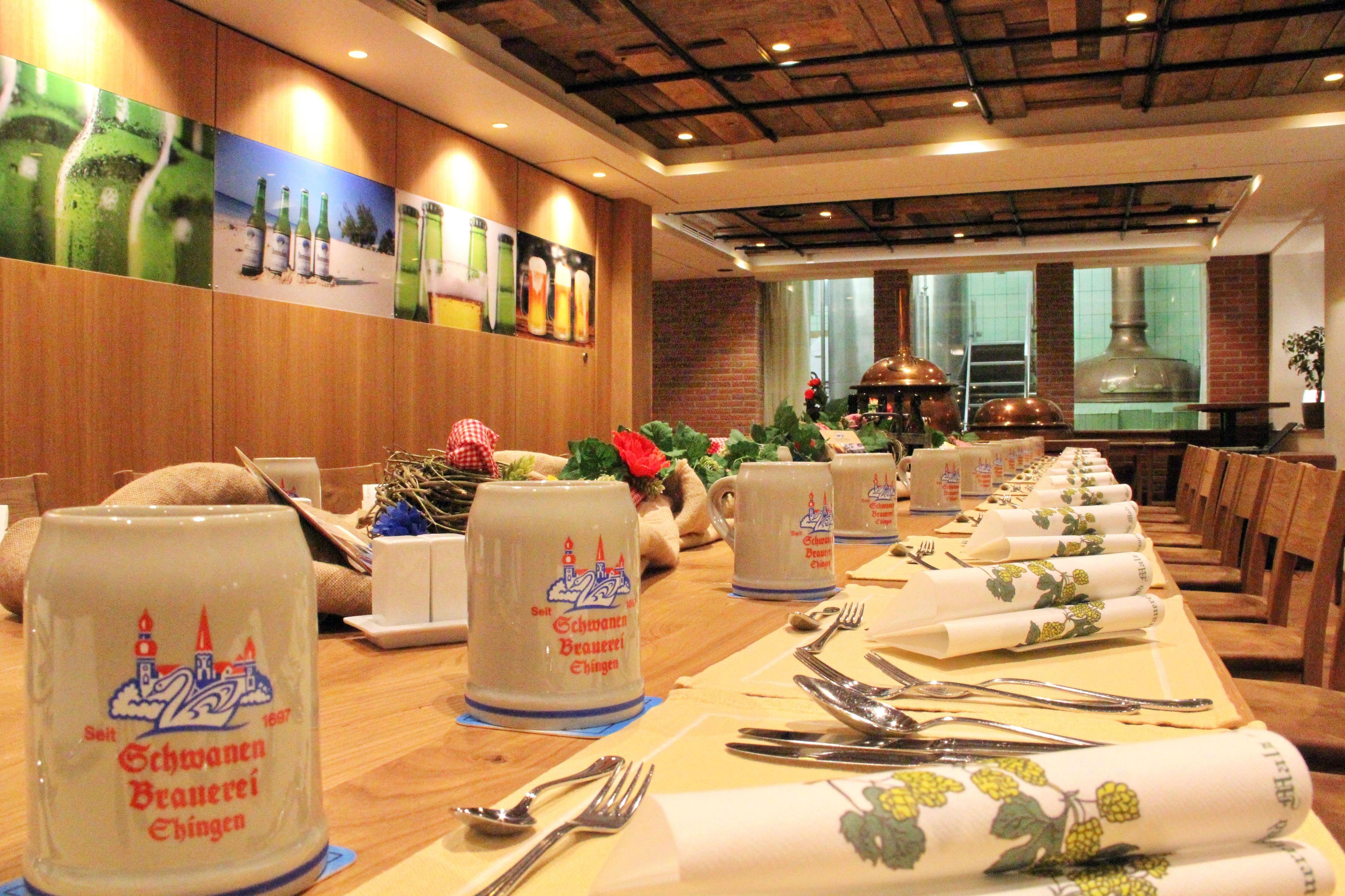 Un restaurante con mesas largas dispuestas para comer, con una jarra de cerveza bávara tradicional como elemento central.