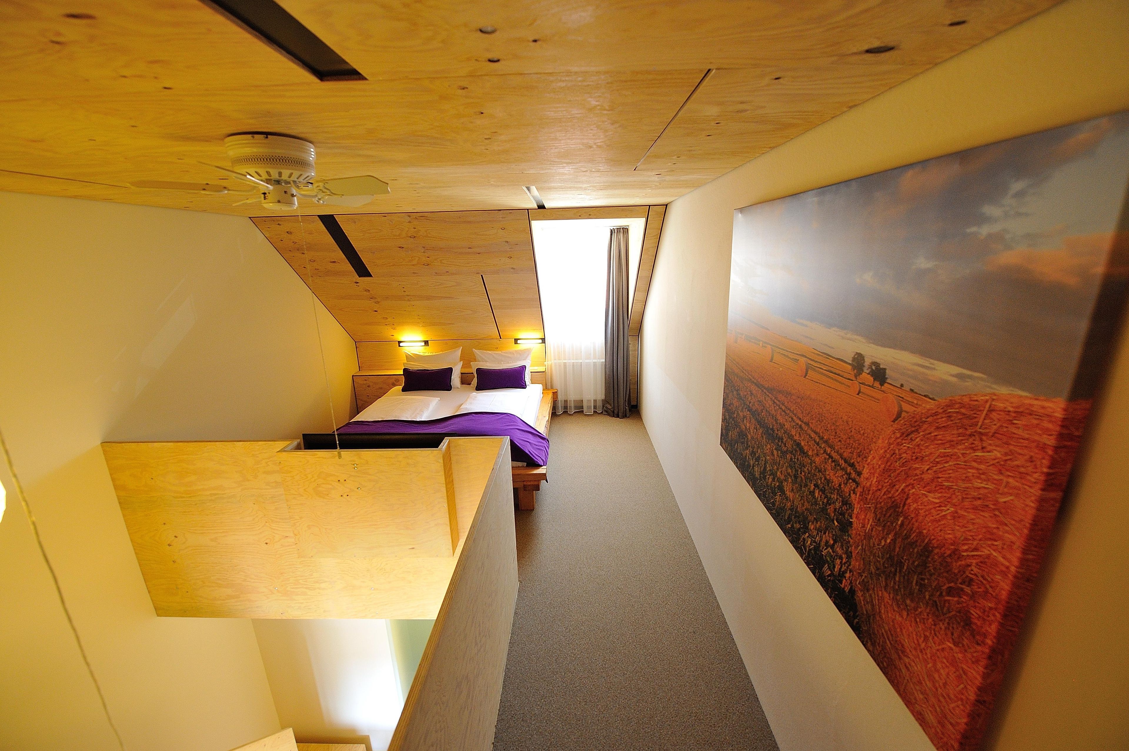Una habitación con una cama, un escritorio y un cuadro grande de paisaje en la pared.