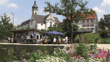 Eine Kirche mit einem Glockenturm, ein Teich mit Blumen und ein Gebäude mit rotem Dach.