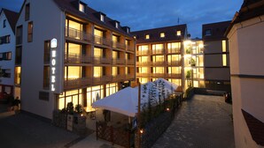 Een hotel met meerdere balkons, een overdekt terras en een geplaveid binnenterrein.